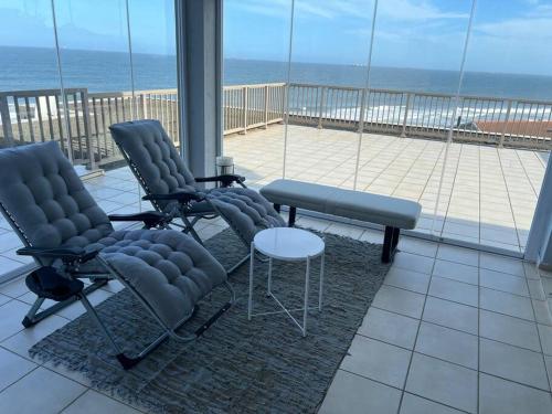 3 chaises et une table sur un balcon donnant sur l'océan dans l'établissement A quintessential work-relax space, à La Mercy