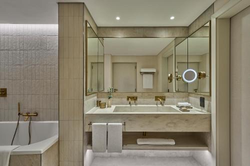 a bathroom with a large sink and a tub at ERTH Abu Dhabi Hotel in Abu Dhabi
