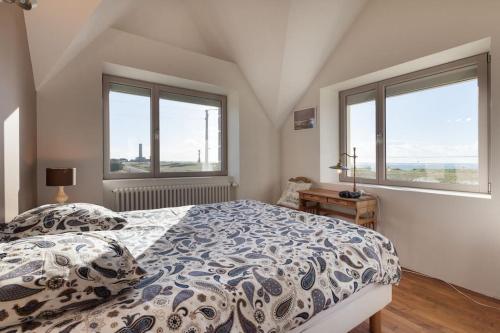 a bedroom with a bed and two windows at La Villa de Pascal, vue mer in Penmarch