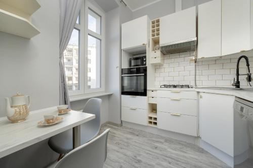 - une cuisine avec des placards blancs, une table et des chaises dans l'établissement Spacious 3-Bedroom Apartment Plac Grunwaldzki Wrocław by Renters, à Wrocław