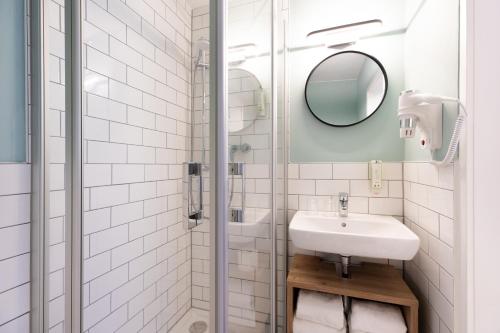 een witte badkamer met een wastafel en een spiegel bij Yggotel Pirol in Keulen