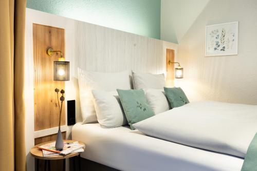 a bedroom with a white bed with pillows at Yggotel Pirol in Cologne