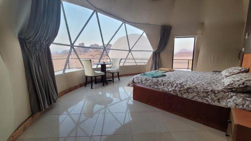 ein Schlafzimmer mit einem Bett und einem Tisch und Fenstern in der Unterkunft Rum Gonesh Luxury Camp in Wadi Rum
