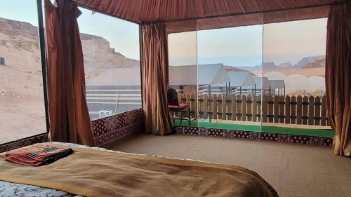 a room with a bed and a large window at Rum Gonesh Luxury Camp in Wadi Rum