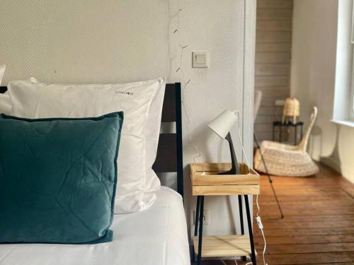 - un lit avec un oreiller vert et blanc et une lampe dans l'établissement Cocon boisé x Parking by Melrose, à Bayeux
