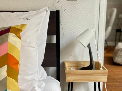 a black brush in a wooden box next to a bed at Cocon boisé x Parking by Melrose in Bayeux