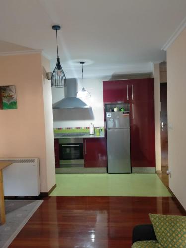 a kitchen with red cabinets and a stainless steel refrigerator at El rinconcito de Aldán in Aldán