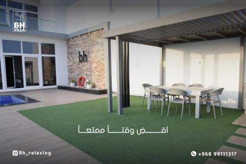 una zona de comedor con mesa y sillas en una casa en bh villa en Al Ashkharah