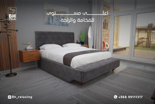 1 dormitorio con 1 cama grande y mesita de noche en bh villa en Al Ashkharah