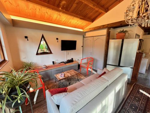 sala de estar con sofá blanco y cocina en Vakantiechalet voor 4 plus 2 met sauna, en Lanaken