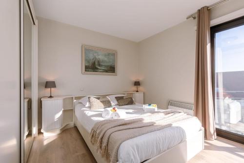 - une chambre avec un grand lit blanc et une fenêtre dans l'établissement Spacious & modern sea view apartment with garage, à Ostende
