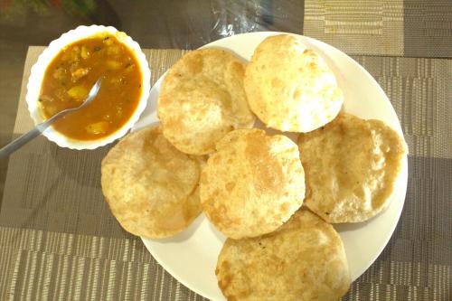 um prato branco com biscoitos e uma tigela de molho em Hotel Shivaay em Ahmedabad