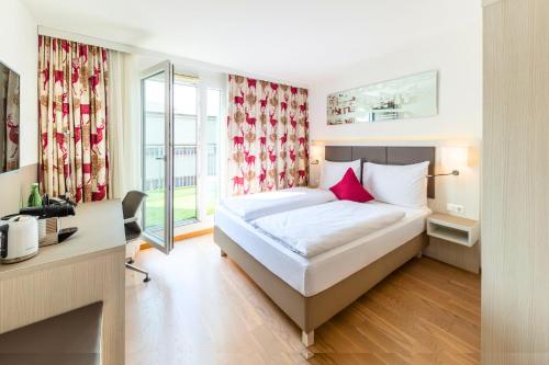 a bedroom with a bed and a desk and a window at Hotel Zeitgeist Vienna Hauptbahnhof in Vienna