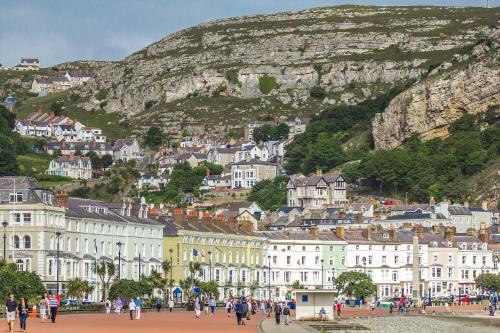 Cosy 1 Bedroom Apartment in the Heart of Llandudno في خلنددنو: مجموعة من الناس يتجولون في مدينة بها جبل