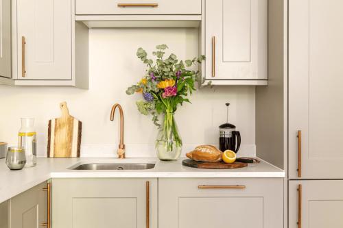 a kitchen counter with a vase of flowers and a sink at Cohost Partners | Close to City Centre | One BR! in Cardiff