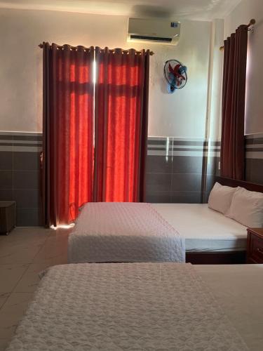 a bedroom with two beds and a red curtain at VIEW HOTEL- TRÀM CHIM in Tràm Chim