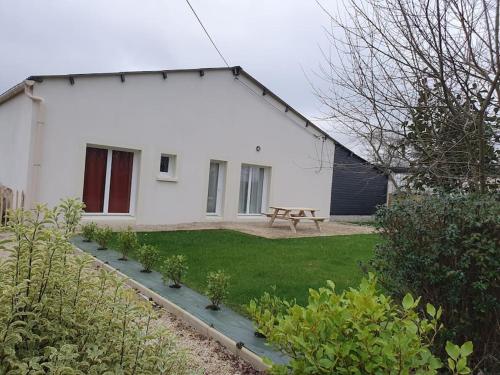 une maison blanche avec un banc devant dans l'établissement Gîte Le Chardonneret 2 étoiles 4 personnes, Jugon les lacs, Côtes d'armor, à Saint-Igneuc
