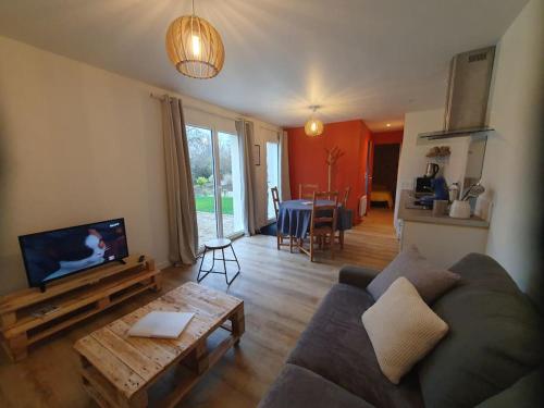 ein Wohnzimmer mit einem Sofa und einem Tisch in der Unterkunft Gîte Le Chardonneret 2 étoiles 4 personnes, Jugon les lacs, Côtes d'armor 