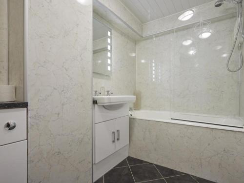 een witte badkamer met een bad en een wastafel bij 1 Bed in Keswick SZ468 in Keswick