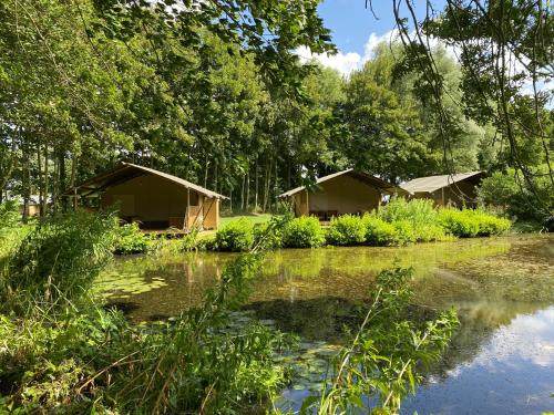 a couple of huts next to a body of water at Luxe safaritent aan het water - Recreatiepark de Uilenburg - Sneek - Friesland in Hommerts