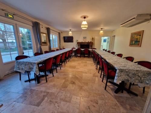 una fila de largas mesas y sillas en una habitación en DSN - Domaine Suisse Normande, en Croisilles