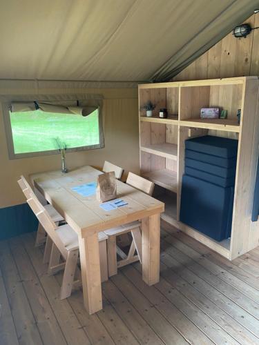 a table and chairs in a tiny house at Luxe safaritent aan het water in Hommerts