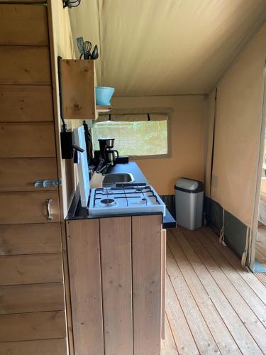 a kitchen with a stove and a sink in a tent at Luxe safaritent aan het water - Recreatiepark de Uilenburg - Sneek - Friesland in Hommerts