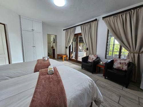 a bedroom with a bed and two chairs and windows at Ndiza Lodge and Cabanas in St Lucia