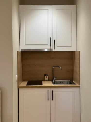 a kitchen with white cabinets and a sink at Arial Lofts in Vlorë