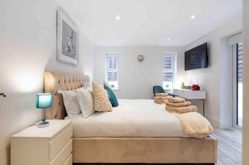 a white bedroom with a large bed and a table at Wanstead, Escape London in London-Luxury 2 Bed in London