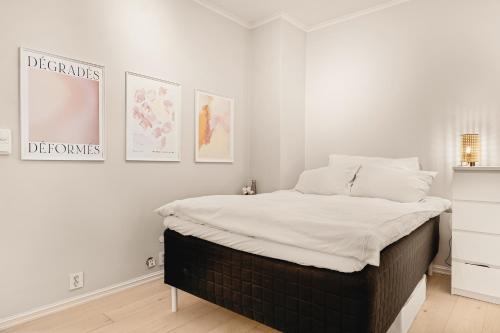 a bed in a bedroom with three pictures on the wall at Dinbnb Apartments I Best of Both Worlds I 80sqm with 2 baths and Bathtub in Bergen