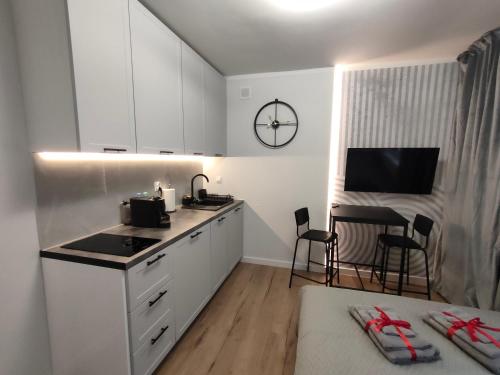 a kitchen with white cabinets and a table with chairs at Slate Apartament Polanica - Zdrój in Polanica-Zdrój