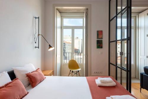 een slaapkamer met een groot wit bed en een gele stoel bij São Bento Bright Studio in Porto