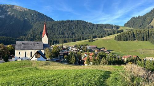a small village with a church on a green hill at Almtraum Berwang in Berwang
