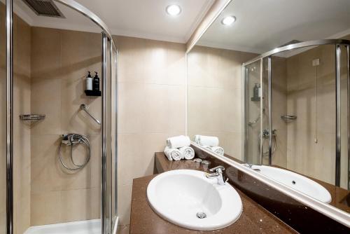 een badkamer met een douche, een wastafel en een bad bij Pedi Beach Hotel in Symi