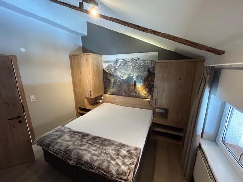 Cette petite chambre comprend un lit orné d'une peinture murale. dans l'établissement Almtraum Berwang, à Berwang