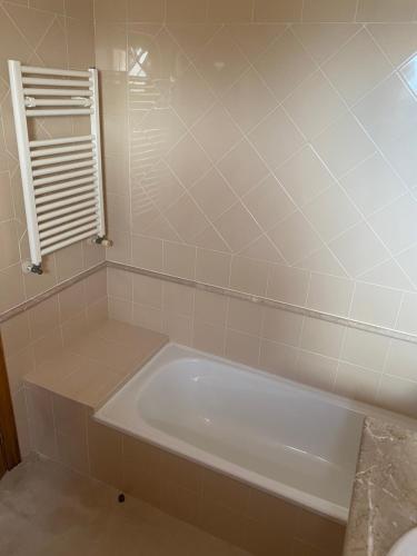 a white bath tub in a bathroom with a window at Villa avec piscine dans un golf in Palmela