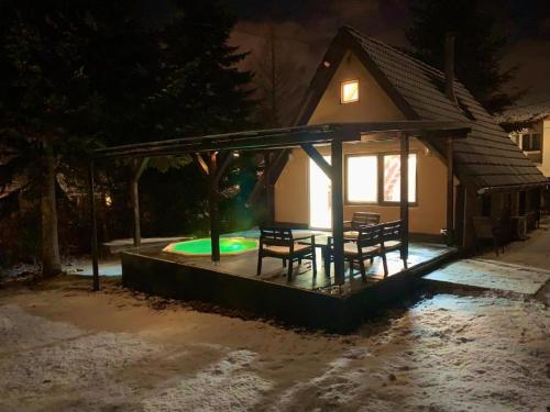 un cenador con una mesa y bancos en la nieve por la noche en Vadgalamb Apartman & Jacuzzi, en Miskolctapolca