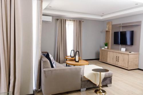 a living room with a couch and a tv at Uptown Luxury Villas in Nelspruit