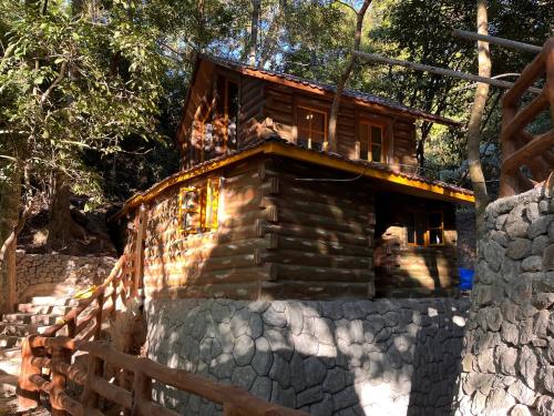 uma cabana de madeira numa parede de pedra com uma cerca em The Forest Creek Cabin 