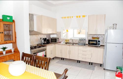 a kitchen with white cabinets and a table and a refrigerator at CASA NATALIA - Guesthouse in Luanda