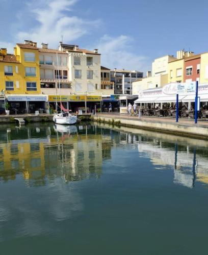 un bateau est amarré dans une rivière près de bâtiments dans l'établissement Séjour voilier port de Gruissan, à Gruissan