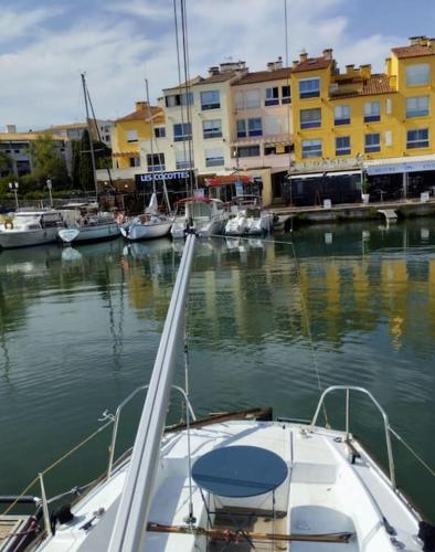 un bateau est amarré dans un port avec des bâtiments dans l'établissement Séjour voilier port de Gruissan, à Gruissan