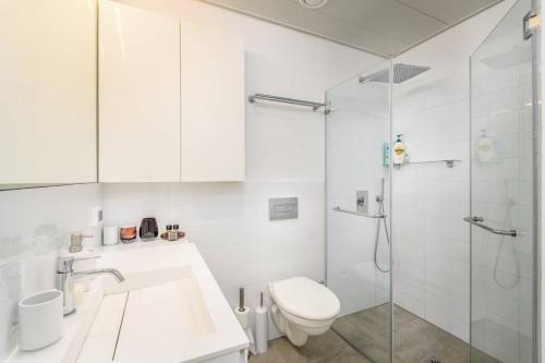 a white bathroom with a toilet and a shower at MAMAD High Standard 3BR Gymnasia Parking Sea view in Tel Aviv