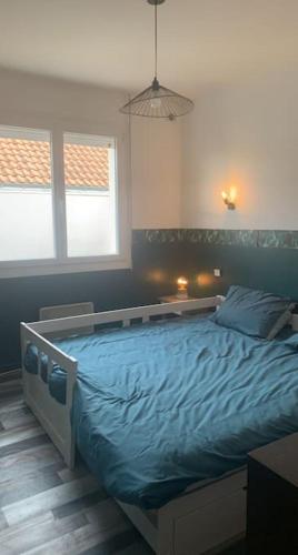 une chambre avec un grand lit avec des draps bleus dans l'établissement Maison a étages bord de mer, à Notre-Dame-de-Monts