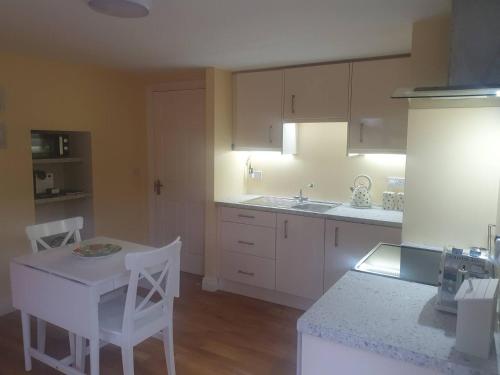 a kitchen with white cabinets and a white table and chairs at Alt Mór House Garden Studio-Self Catering Sleeps 2 in Portnoo