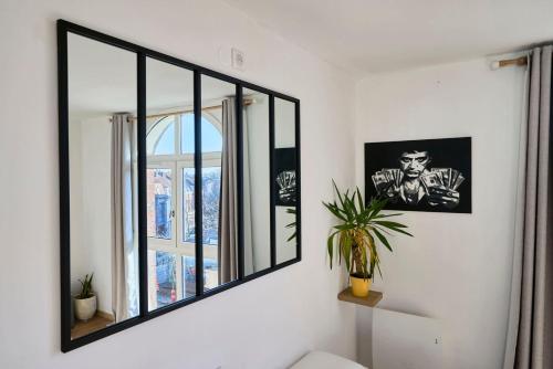 un miroir sur un mur dans une pièce avec une plante dans l'établissement Bright apartment in hypercenter with parking, à Tourcoing