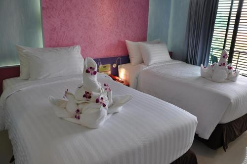 two white beds with flowers on them in a room at The Gallery At Koh Chang in Ko Chang