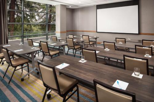 a conference room with tables and chairs and a screen at Hyatt House San Jose/Cupertino in Cupertino