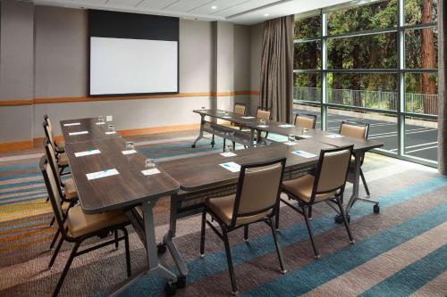 a conference room with tables and chairs and a screen at Hyatt House San Jose/Cupertino in Cupertino